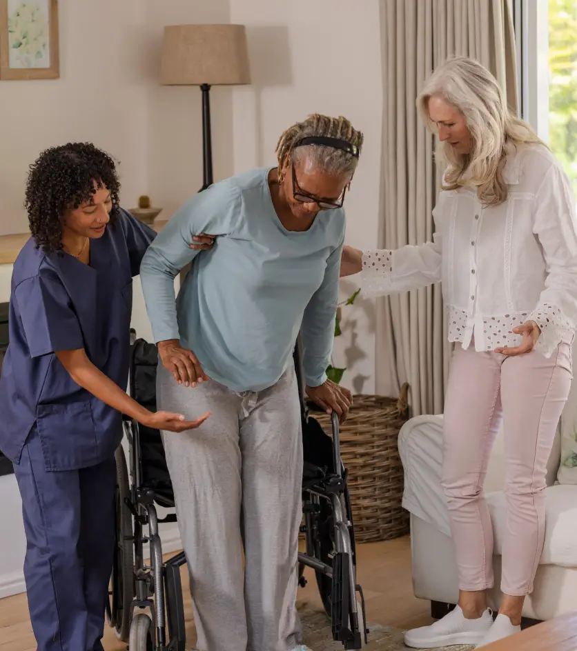 Caregiver and friend assisting senior woman standing from wheelchair at home. Caregiving, support, assistance, mobility, friendship, healthcare